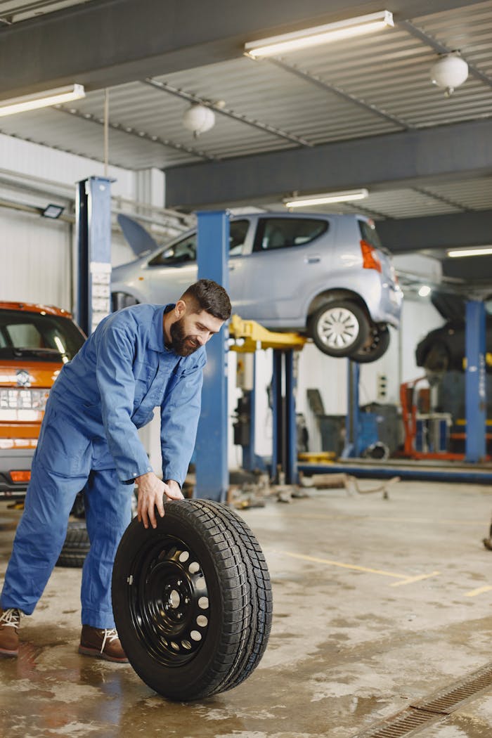 The Art of Drawing Readers In: Your attractive post title goes here Mechanic handling a tire in a busy automotive repair workshop.